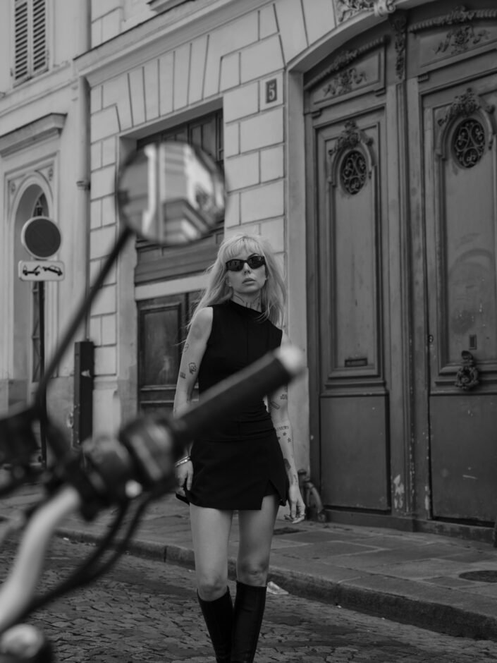 Portrait de Shai en tenue moto dans une rue parisienne